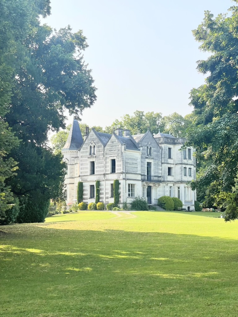 A stunning view of Chateau Charente taken from the lush gardens, featuring elegant stone architecture surrounded by vibrant greenery.